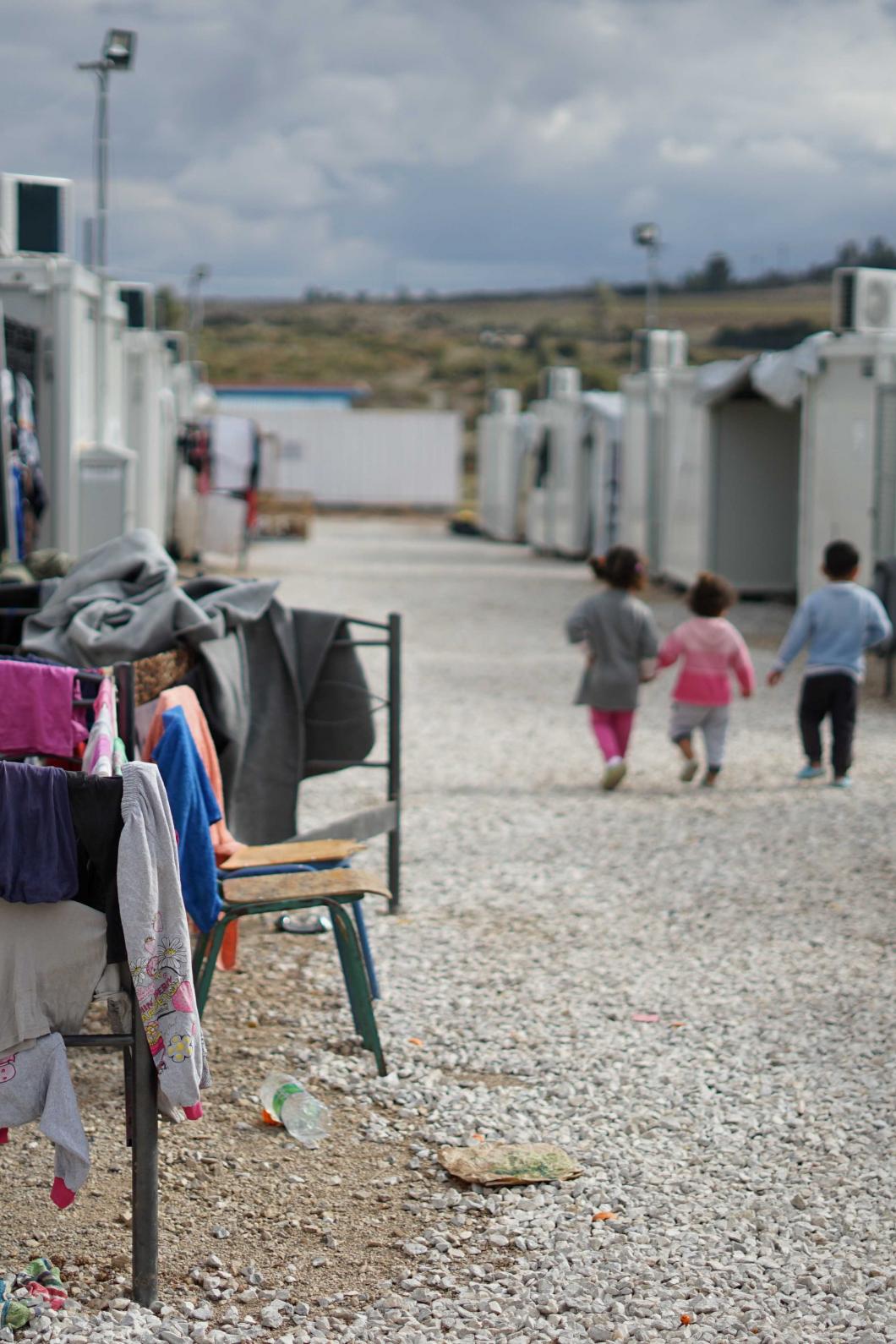 Kinderen lopen langs wasrekken in een vluchtelingenkamp in Griekenland