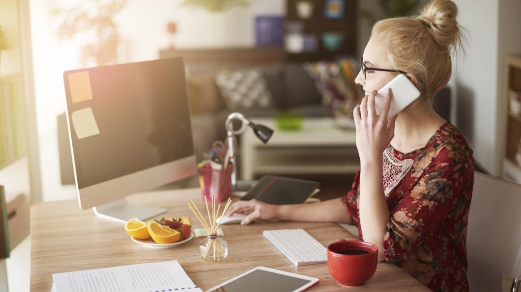 Een vrouw zit bellend achter haal laptop