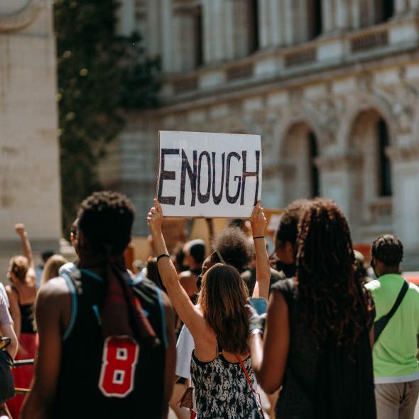 vrouw houdt bord vast met 'enough' tekst tijdens protest
