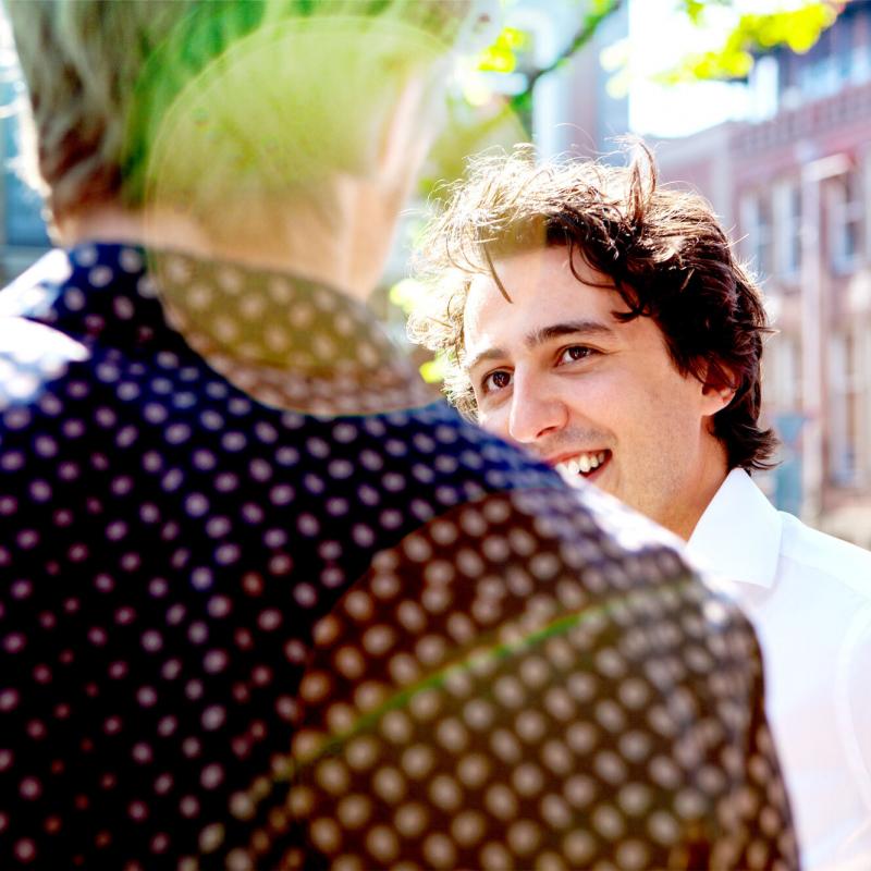 Jesse Klaver lachend naar een persoon waarvan wij alleen de rug zien. 